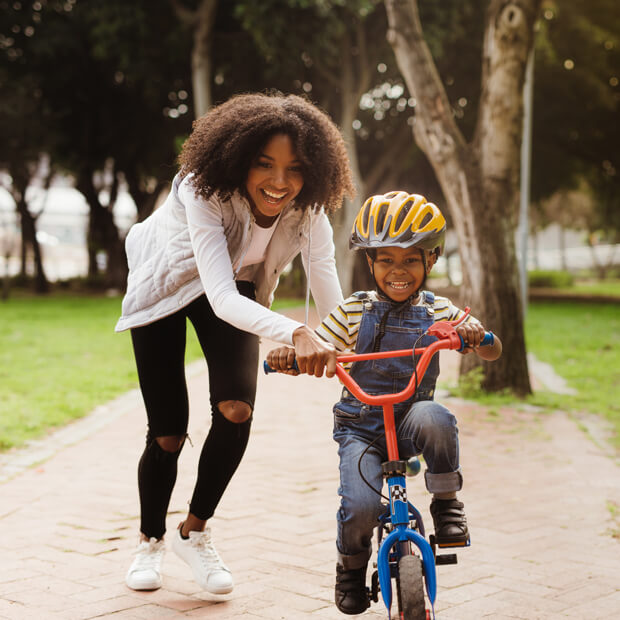 A woman teaching a young boy how to ride a bicycle